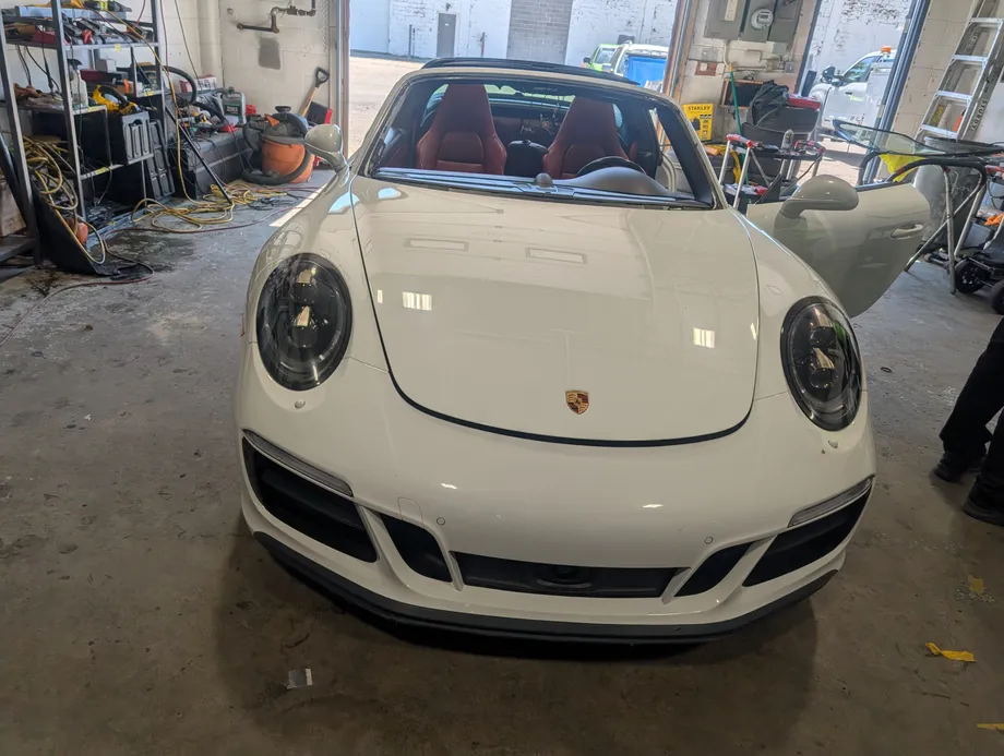 Windshield replacement in-progress of a white Porsche Cayman at s Stealth garage