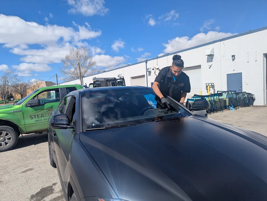 Stealth technician on a mobile repair fixing a windshield chip on a black Lamborghini Urus